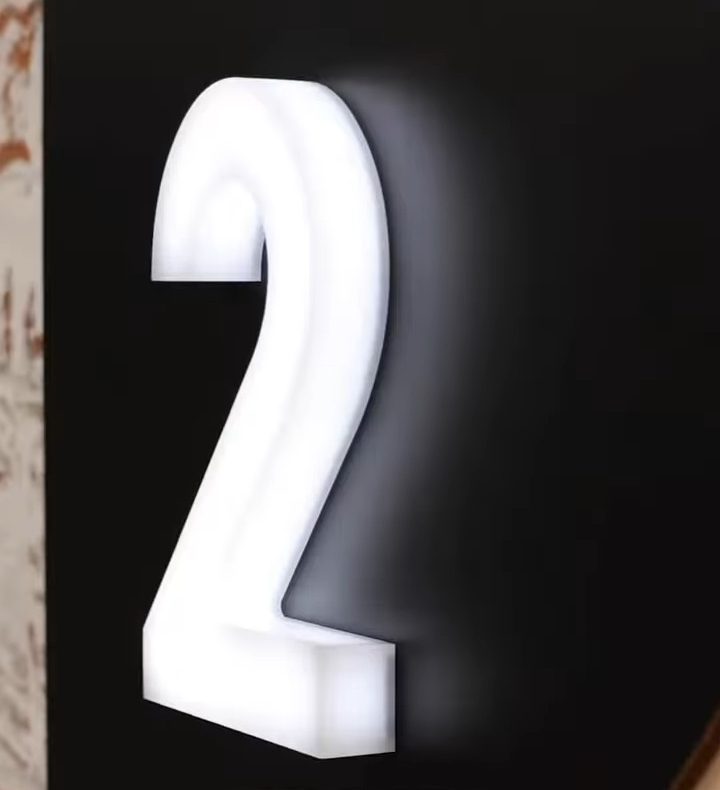 Número 2 em acrílico branco, iluminado por dentro, sobre fundo preto
